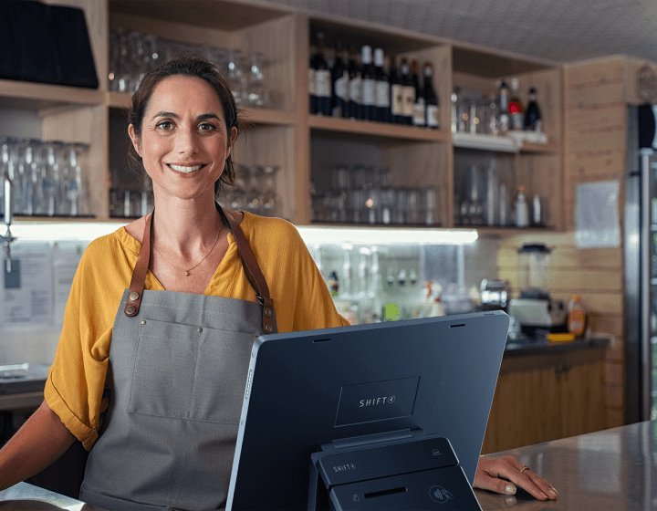 Woman standing and smiling at shop counter.